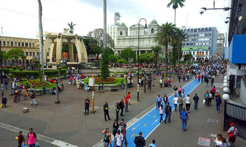 Picture of a street scene in San Jose, Costa Rica.  The picture shows a large square with many people sightseeing and visiting museums.