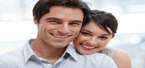 Picture of a smiling couple showing their happiness with their visit to Costa Rica for plastic surgery.  The woman is resting her head on the man’s shoulder and both are facing the camera with a big smile.