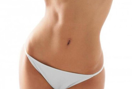 Picture of a woman facing the camera and happy with the perfect abdomen liposuction procedure she had at Top Plastic Surgeons in beautiful San Jose, Costa Rica.  She is wearing a two piece bikini and showing a flat abdomen to the camera.