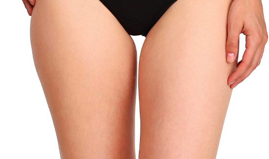 Picture of a trim woman wearing a black bikini bottom, and happy with her perfect thigh lift she had at Top Plastic Surgeons in beautiful San Jose, Costa Rica.  The woman is facing the camera and has both arms down to her sides.
