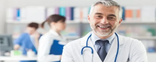 Picture of a plastic surgeon representing the doctors at Top Plastic Surgeons in San Jose, Costa Rica.  The picture shows a doctor in a white coat with a stethoscope around his neck and arms crossed, looking directly at the camera and smiling.